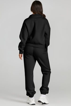 Black quarter-zip sweatshirt and jogger set with cuffed ankles and white sneakers.