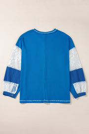 Blue waffle knit top with white lace paneled sleeves and blue accents.