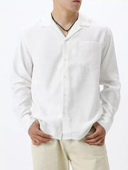 White relaxed camp collar button-up shirt with chest pocket and long sleeves.