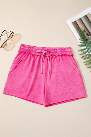 Acid-washed hot pink cotton drawstring shorts with pockets and elastic waistband.
