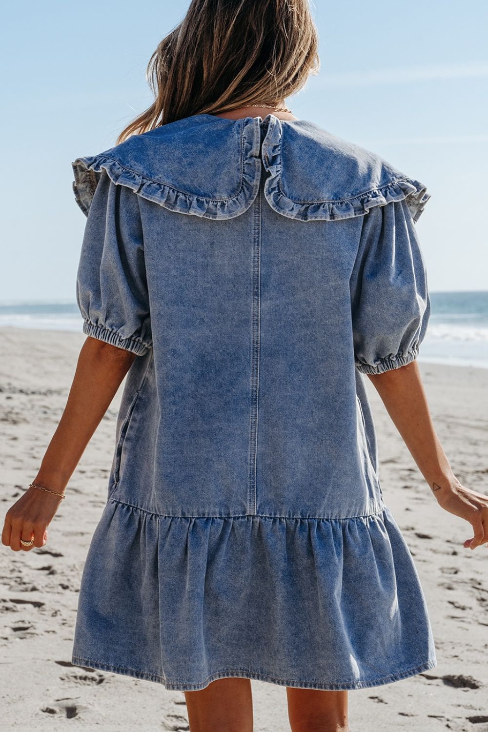 Denim mini dress in medium wash with a ruffled collar, puff sleeves, and tiered hem.