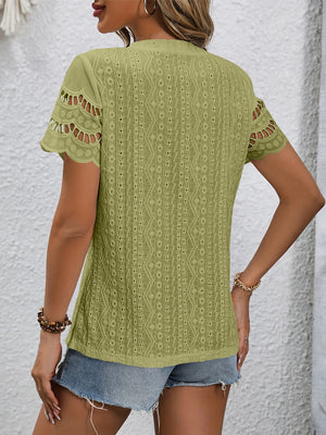 Sage green eyelet blouse with scalloped short sleeves and intricate pattern detail.
