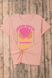 Watermelon pink graphic tee with sunset design and text.
