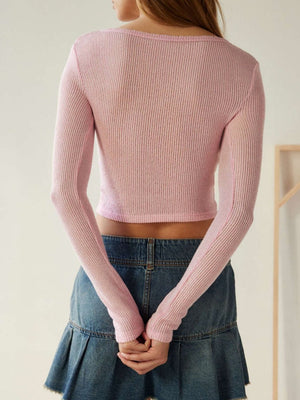 Dusty pink ribbed crop top with long sleeves and a scoop neck, worn with a denim skirt.