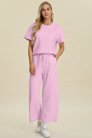 Pink textured knit lounge set with wide leg pants and a short sleeve top.