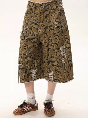 Men's distressed camo denim shorts with frayed hem and cargo pockets.