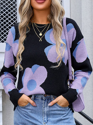 Black oversized knit sweater with large purple and blue floral print, crew neck, long sleeves.