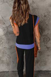 Colorblock sportswear set with black top, light blue and orange trim, and black pants with orange stripe.