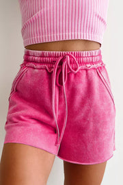 Acid-washed hot pink cotton drawstring shorts with pockets and elastic waistband.