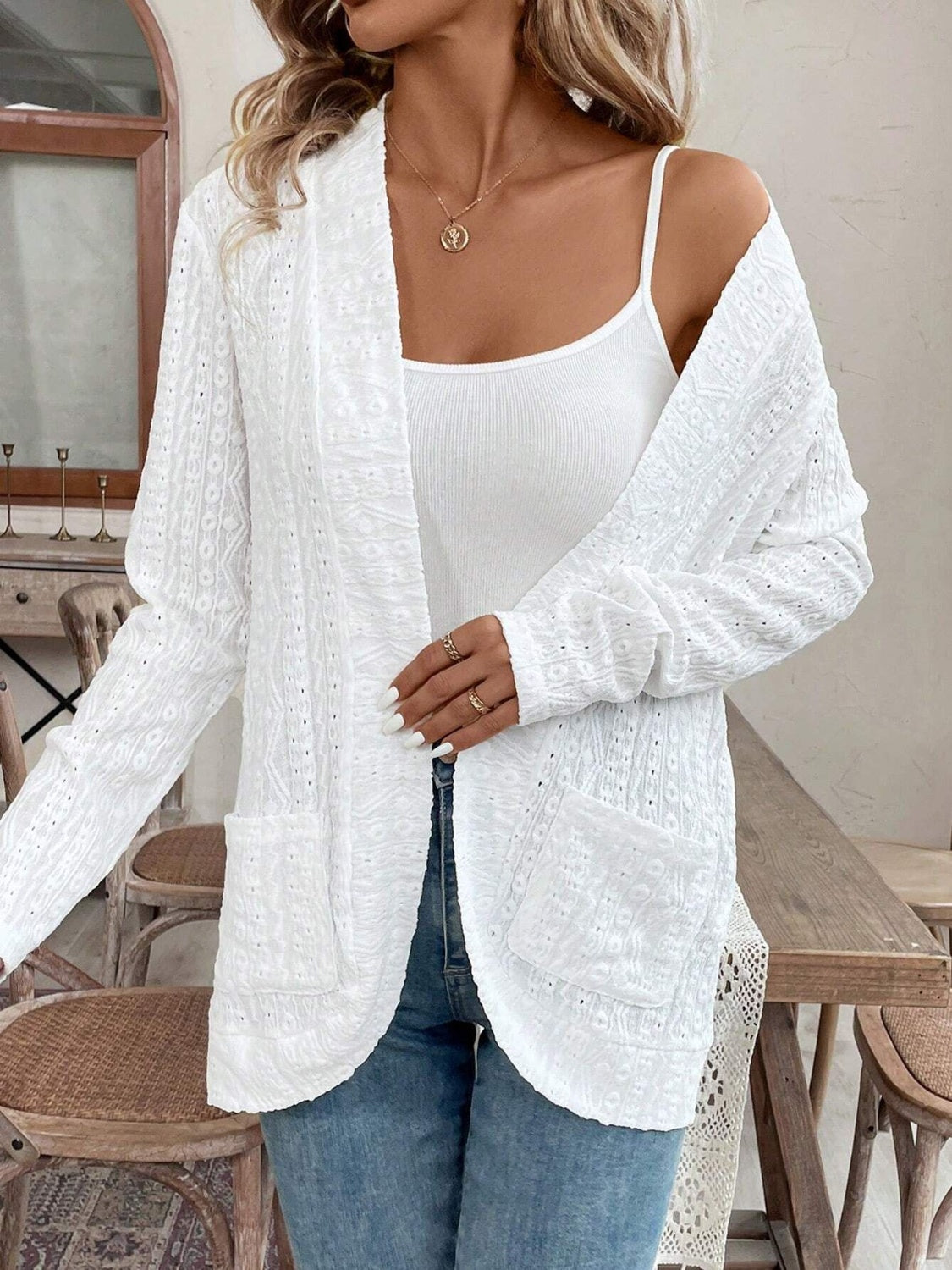 White open-weave embroidered cardigan with pockets and long sleeves, styled over a tank top.