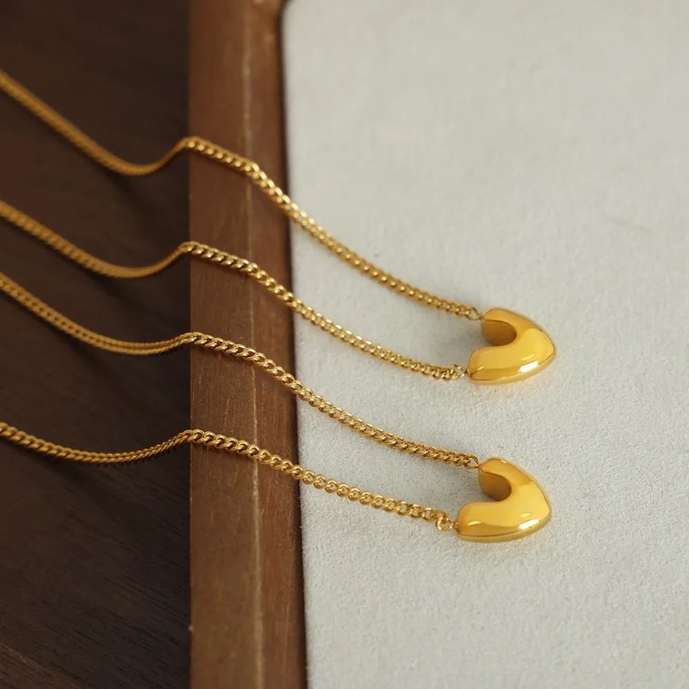 Gold heart charm necklaces with delicate curb chains, elegant everyday wear.