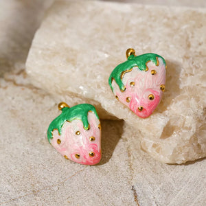Playful strawberry charm earrings with pink and white marbled design, green tops, and gold accents.