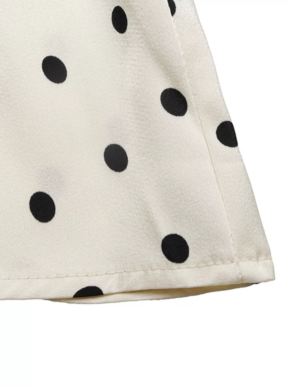 Cream peplum blouse with black polka dots and a ruffled hem detail.