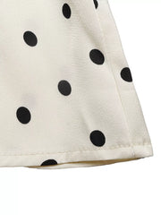 Cream peplum blouse with black polka dots and a ruffled hem detail.