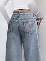 Light wash denim wide-leg jeans with pink embroidered bows on back pockets.