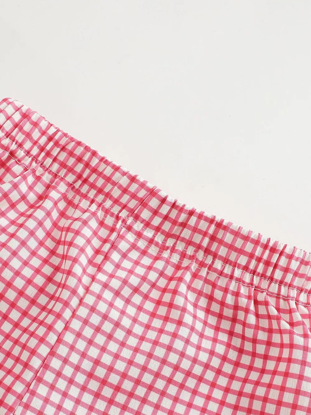 Baby shorts with pink and white gingham pattern and elastic waistband.