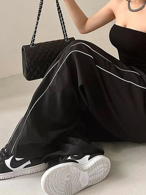 Black wide-leg maternity trousers with white piping detail and gathered waistband.