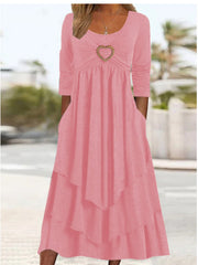 Pink midi dress with long sleeves, ruched bodice, heart detail, and tiered skirt.