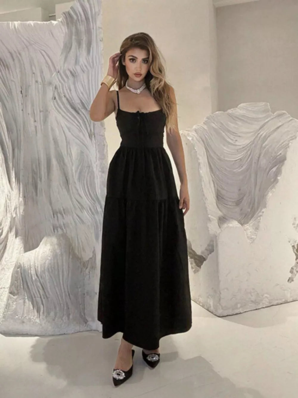 Black backless maxi dress with spaghetti straps and crisscross detail, tiered skirt.
