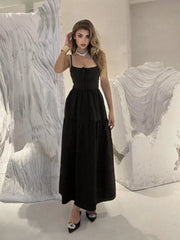 Black backless maxi dress with spaghetti straps and crisscross detail, tiered skirt.