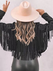Black cropped jacket with fringe detail and open front, styled with a wide-brim hat.