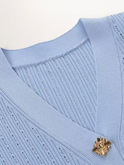 Light blue ribbed knit cardigan with openwork detail and gold button closure.