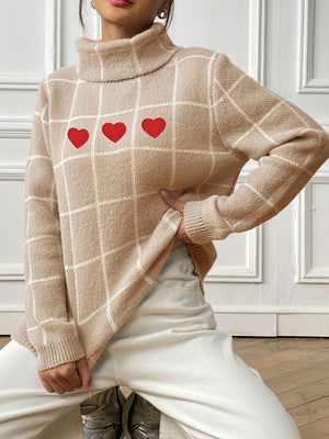 Tan turtleneck sweater with white grid pattern and three red heart appliqués.