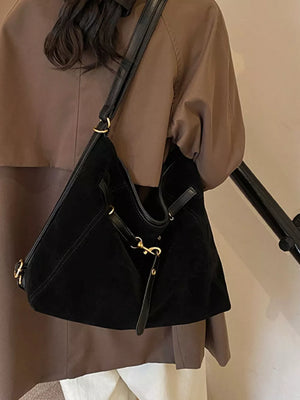 Sleek black slouchy crossbody bag with gold accents and adjustable strap.