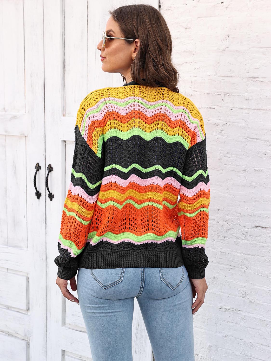 Crochet cardigan with rainbow wave pattern in yellow, pink, orange, green, and black acrylic.