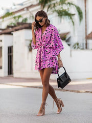 Tropical tiered mini dress in fuchsia pink with a leopard print, surplice neckline, and belted waist.