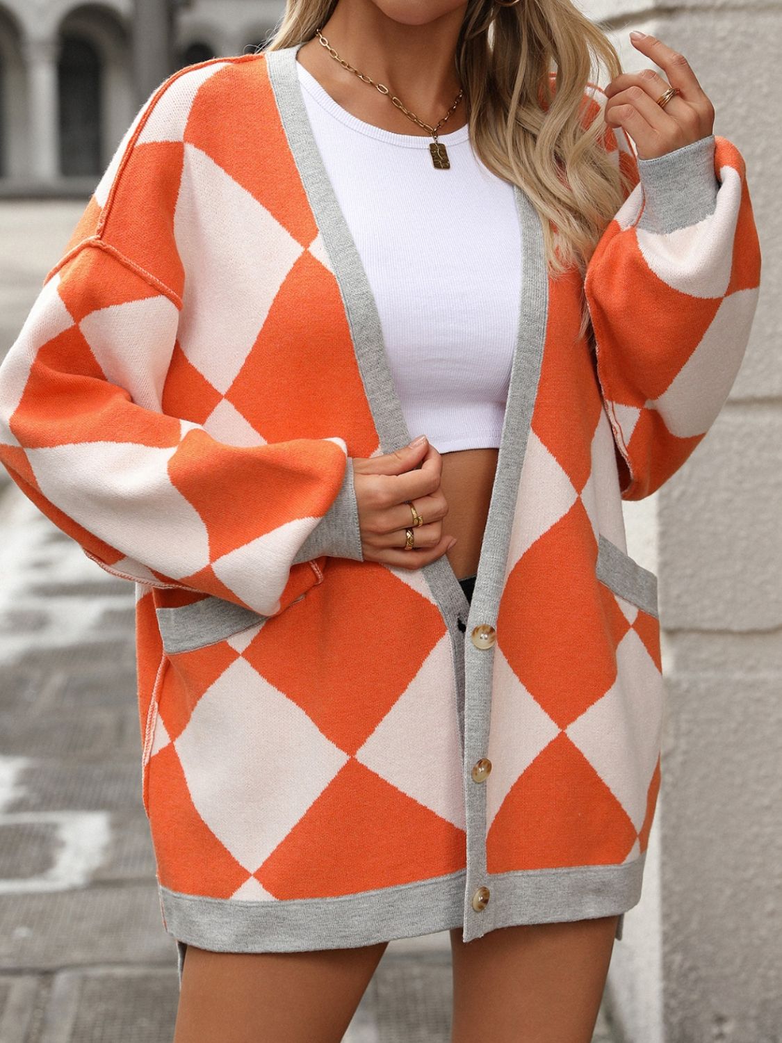 Orange and white argyle knit oversized cardigan with grey trim and pockets.