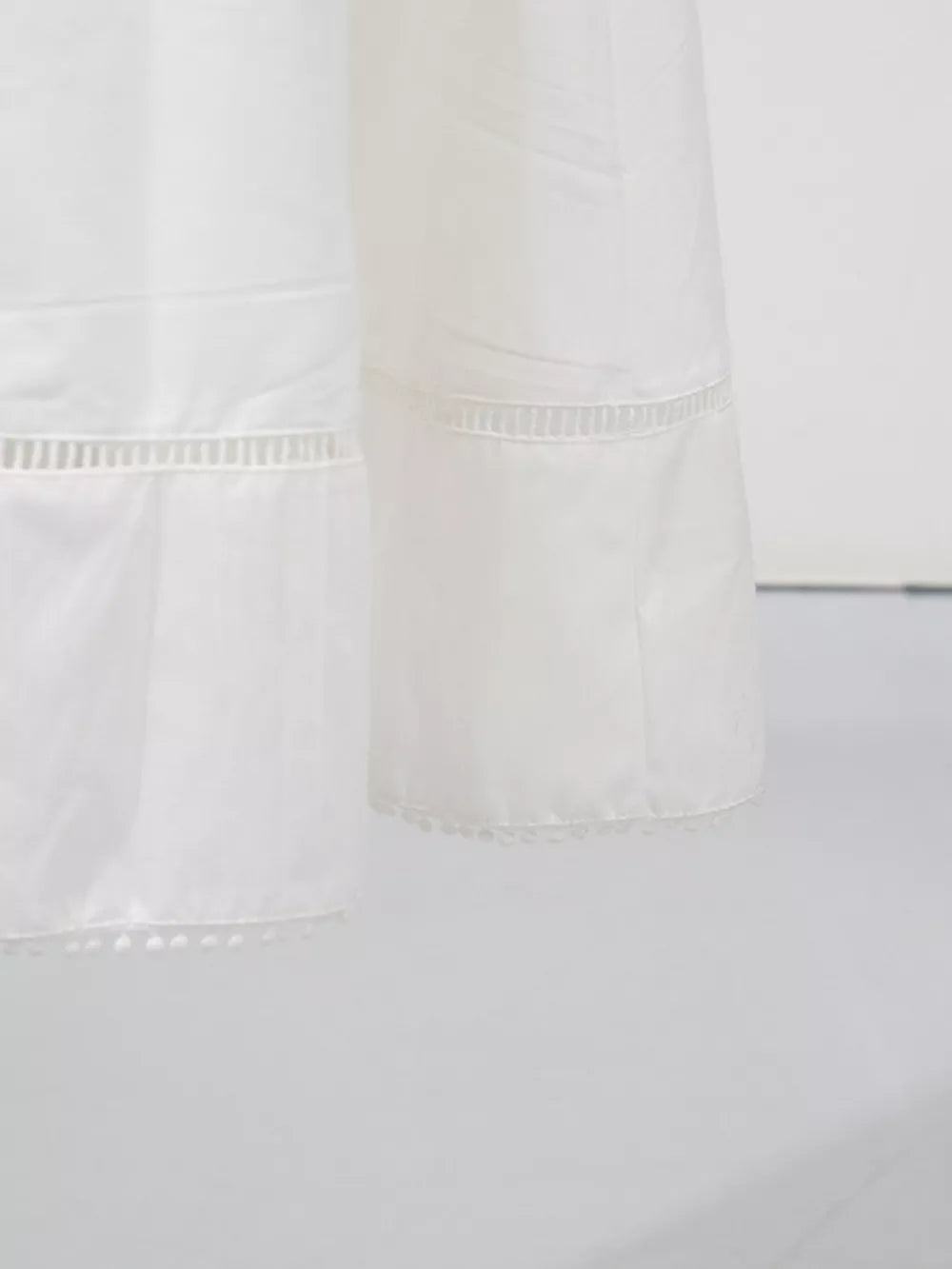 White midi dress with eyelet embroidery detail and pom-pom hem