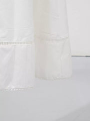 White midi dress with eyelet embroidery detail and pom-pom hem