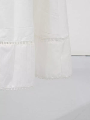 White midi dress with eyelet embroidery detail and pom-pom hem