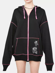 Black zip-up hoodie with pink contrast stitching and rhinestone skull graphics on the pocket.