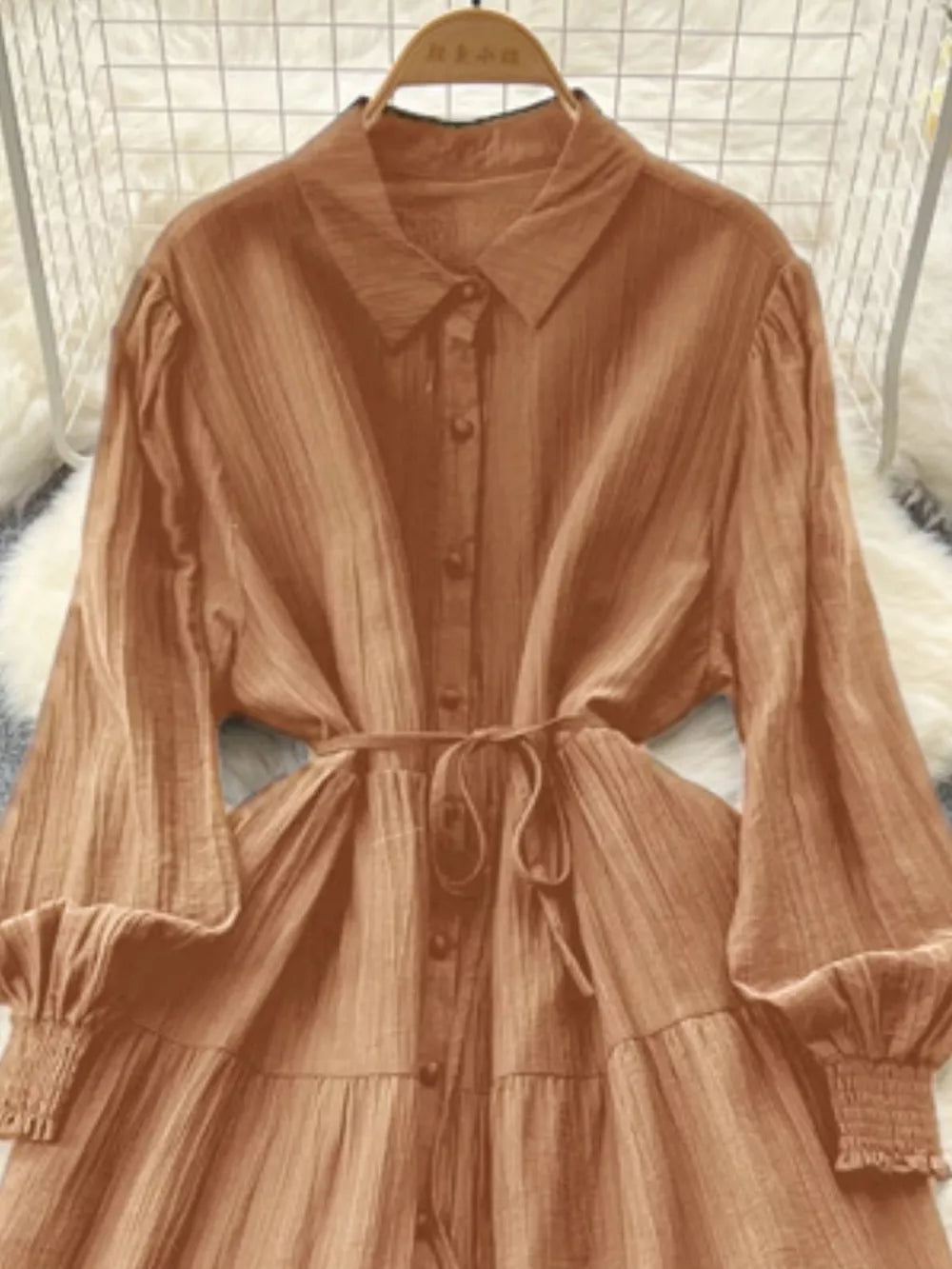 Caramel textured tiered long sleeve button-down dress with cinched waist and smocked cuffs.