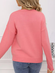 Pink acrylic knit sweater with round neck and bow detail.