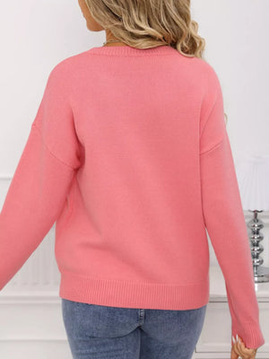 Pink acrylic knit sweater with round neck and bow detail.