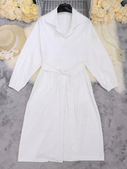 White midi dress with lapel collar, tie waist, and cuffed sleeves.