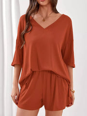 Orange-red ribbed V-neck two-piece lounge set with cuffed sleeves and shorts.