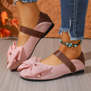 Pink textured round toe flats with large bow detail and brown strap.
