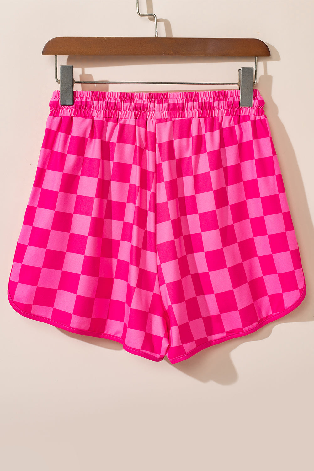 Hot pink checkerboard lounge shorts with elastic waistband and curved hem.