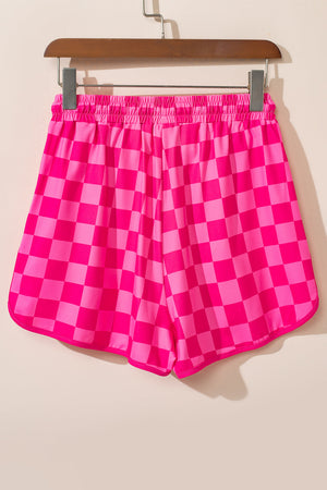 Hot pink checkerboard lounge shorts with elastic waistband and curved hem.
