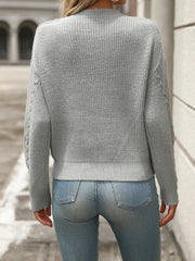 Gray cable knit sweater with crew neck and textured sleeves.
