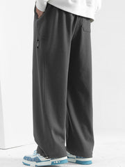 Men's dark gray casual loose-fit drawstring sweatpants with textured fabric and pockets.
