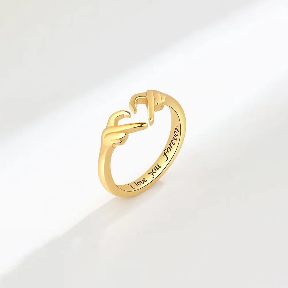 Gold ring with heart hands design and engraved "I love you forever" text.