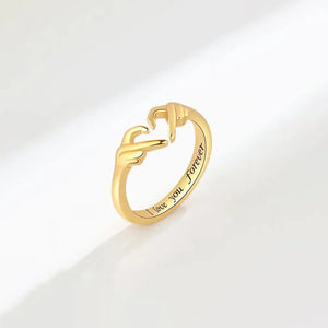 Gold ring with heart hands design and engraved "I love you forever" text.