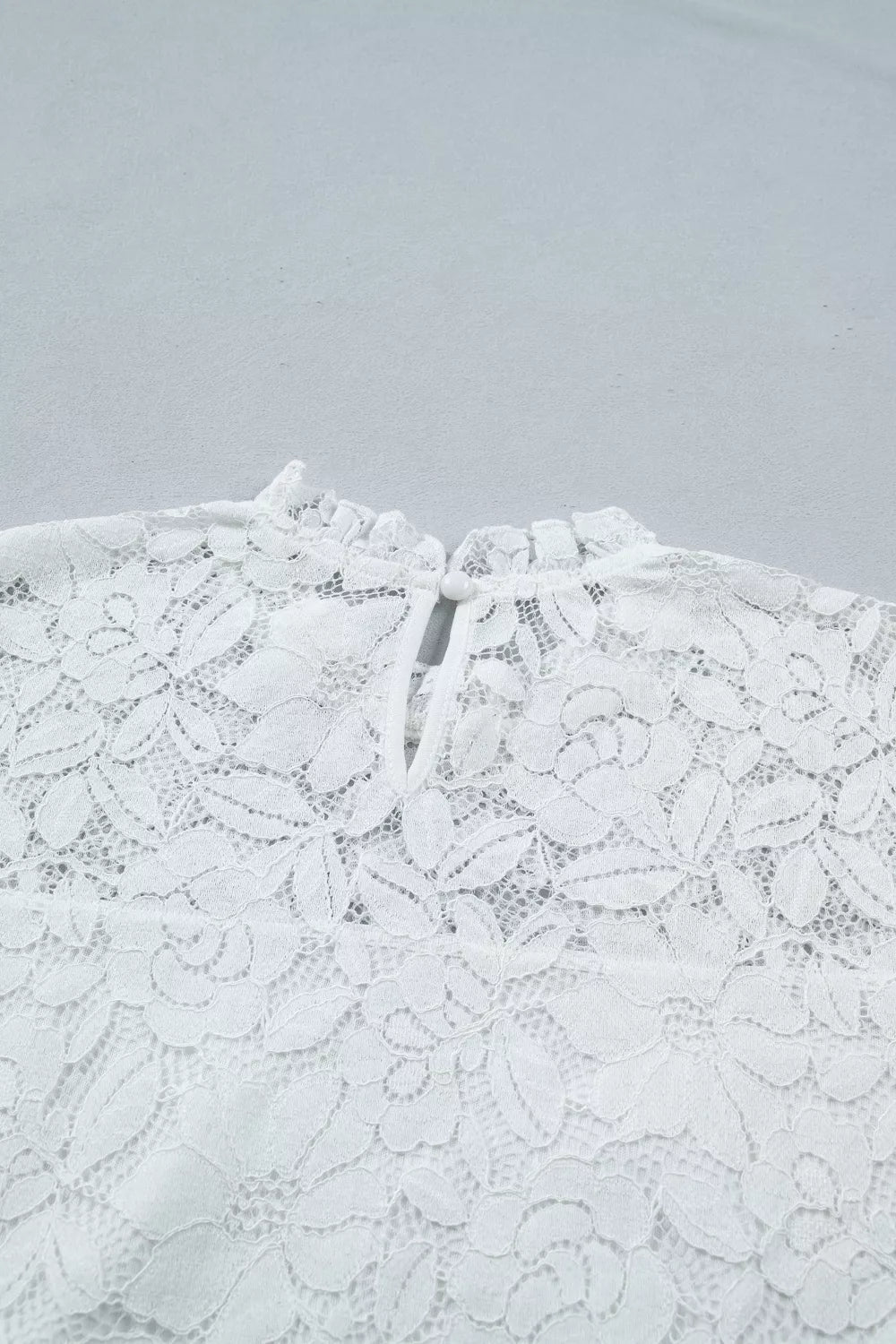 White lace blouse with ruffled neckline and tie closure detail