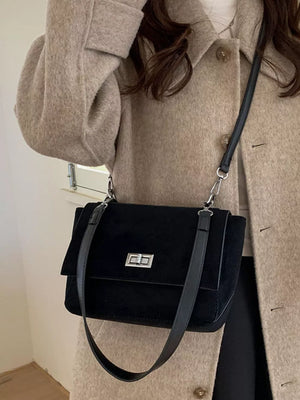 Black suede crossbody bag with flap closure and silver hardware.