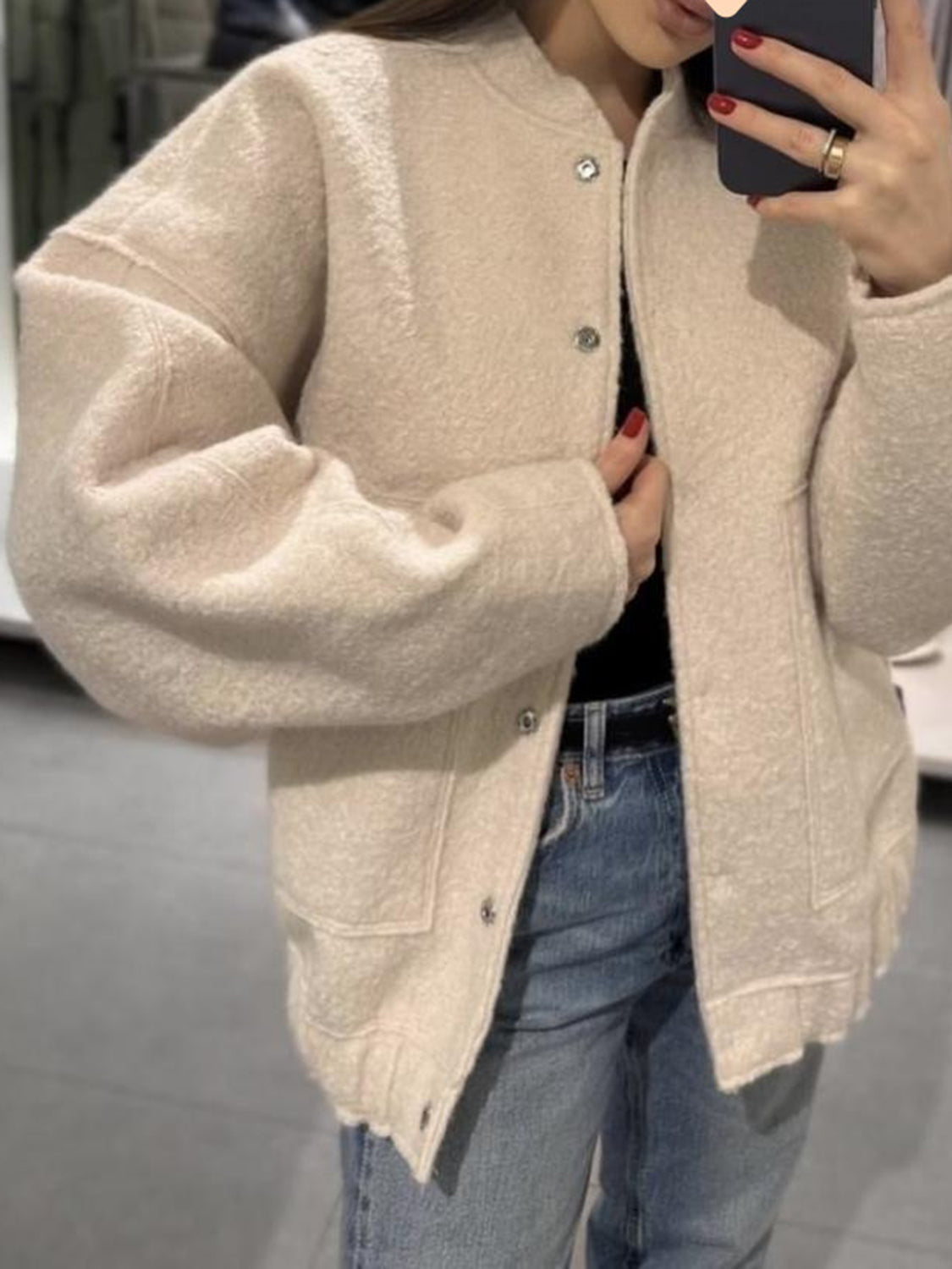 Beige boucle cocoon jacket with snap closure and pockets.
